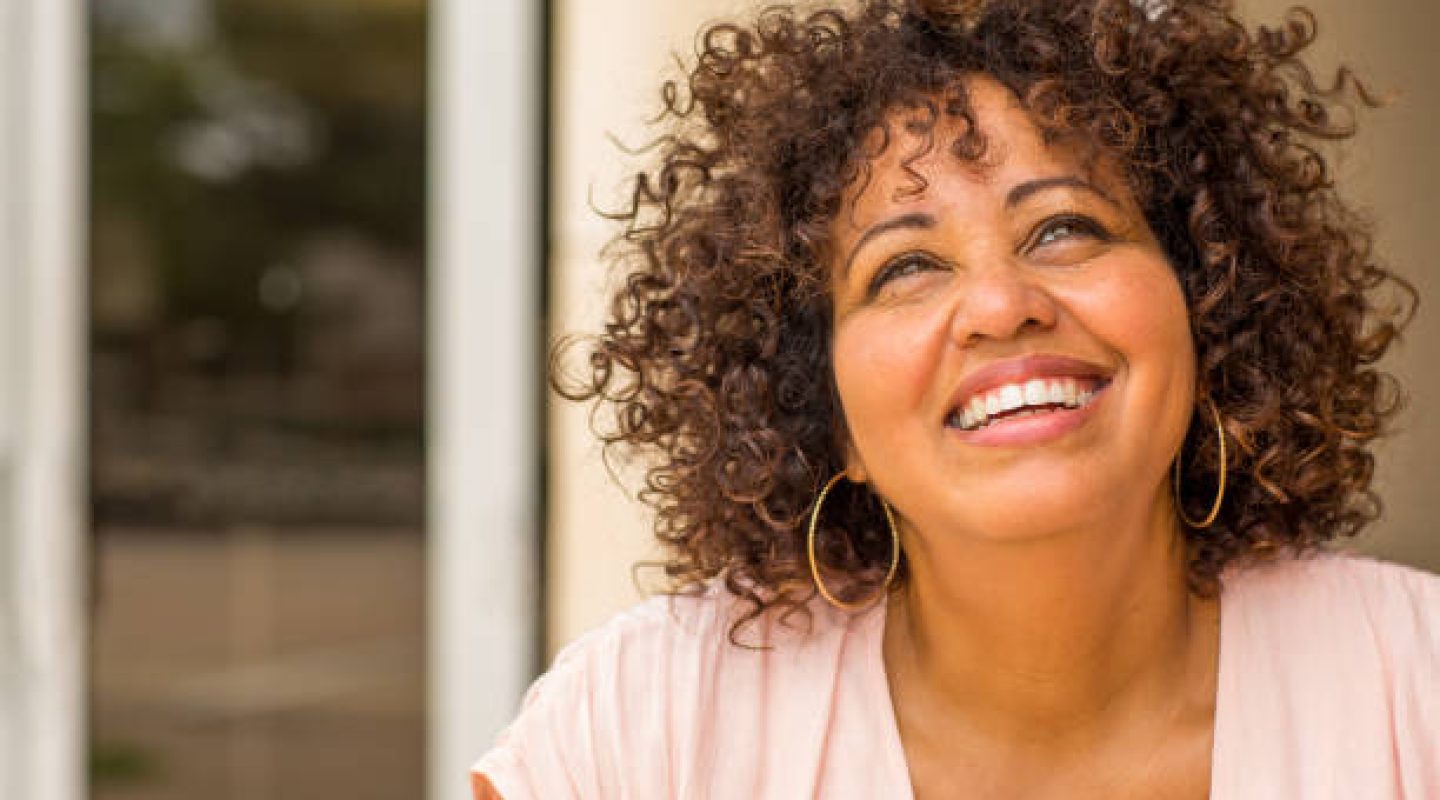 Mixed race mature woman with curly hair  smiling.